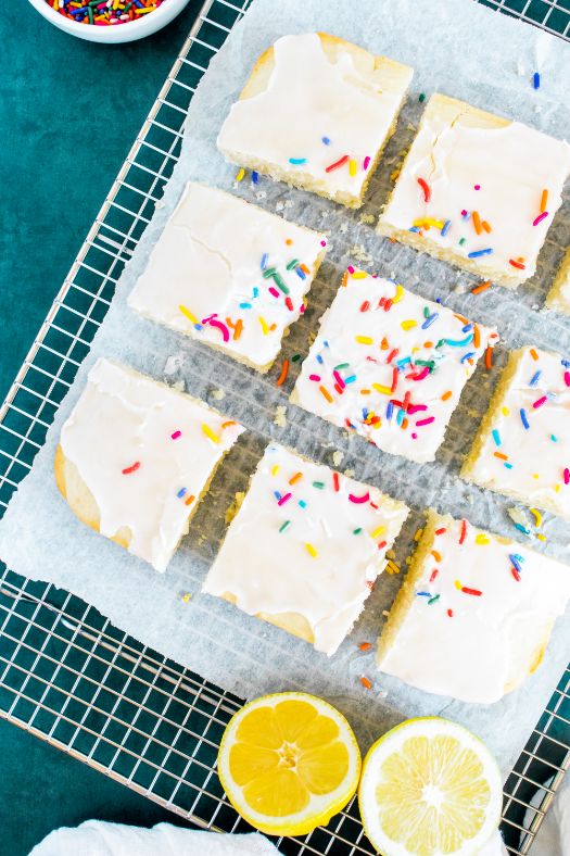 Overhead shot of an iced lemon snack cake cooling on a wire rack and cut into 9 squares