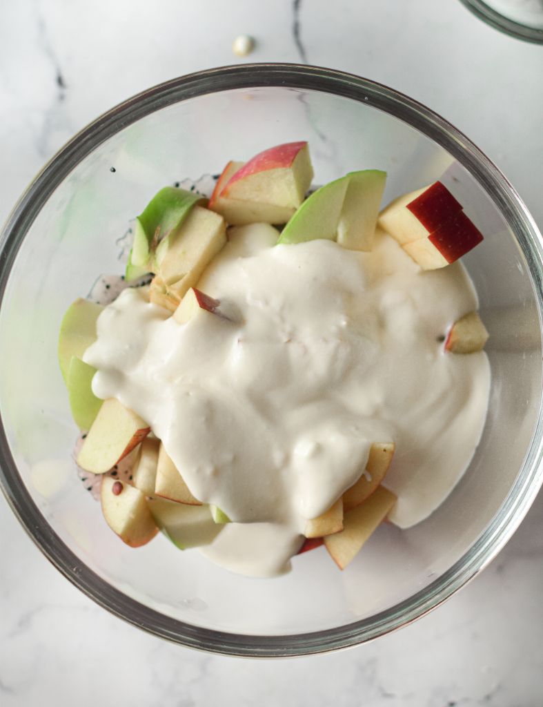An overhead shot of dragonfruit apple and a creamy dressing in a glass bowl