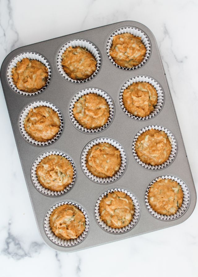 Muffin pan with the cups filled about ¾ of the way full with zucchini muffin batter