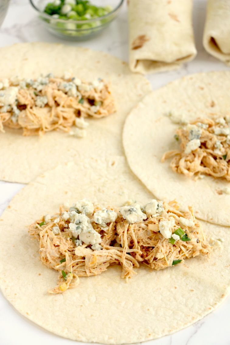 Buffalo chicken mixture added to tortillas, topped with blue cheese and wrapped up