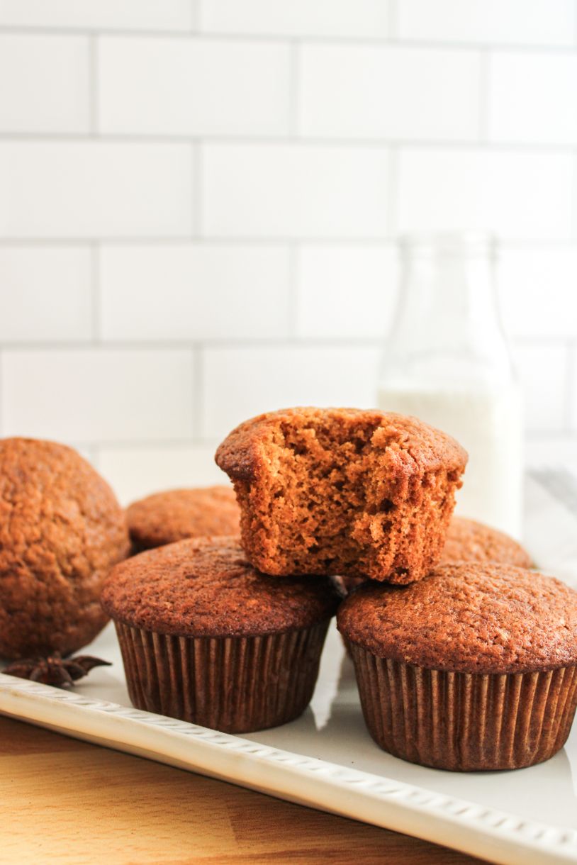 A stack of pumpkin muffins with one muffin on top with a bite out of it