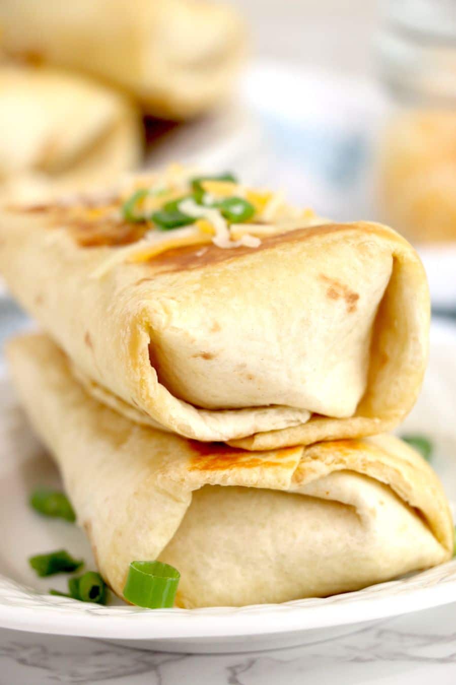 spicy chicken wraps topped one on top of the other with sprinkles of cheese and spring onions