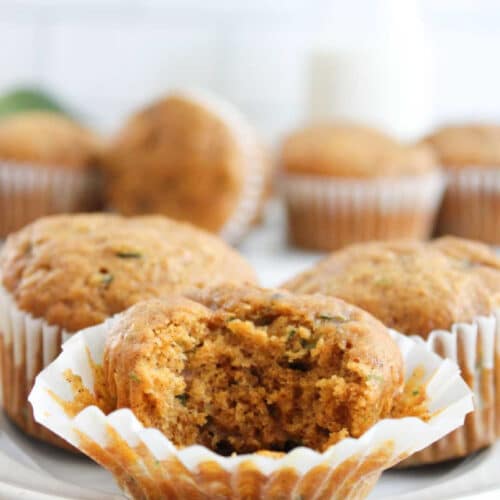 Pumpkin and zucchini muffin served in a white muffin layer with a bite taken out of it