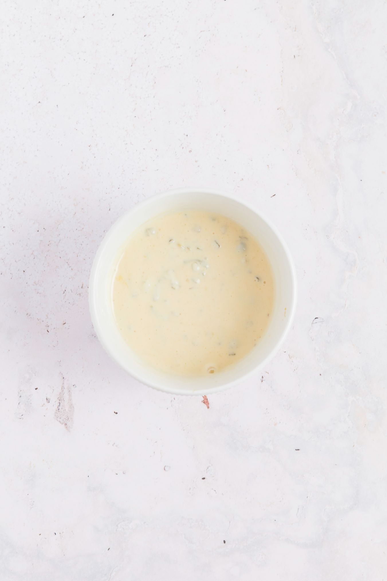 Macaroni salad dressing mixed together in a small white bowl