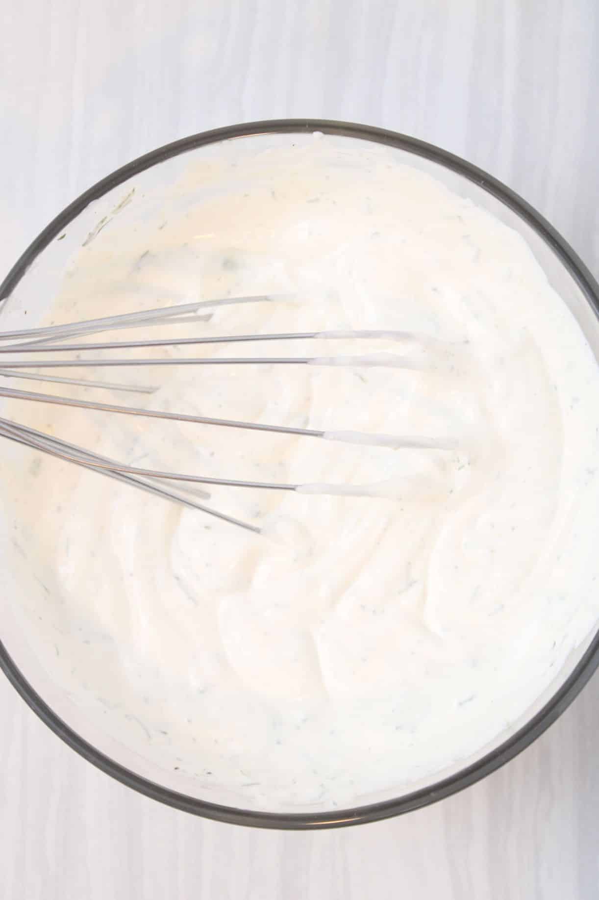 A whisk whisking together ingredients in a large glass bowl