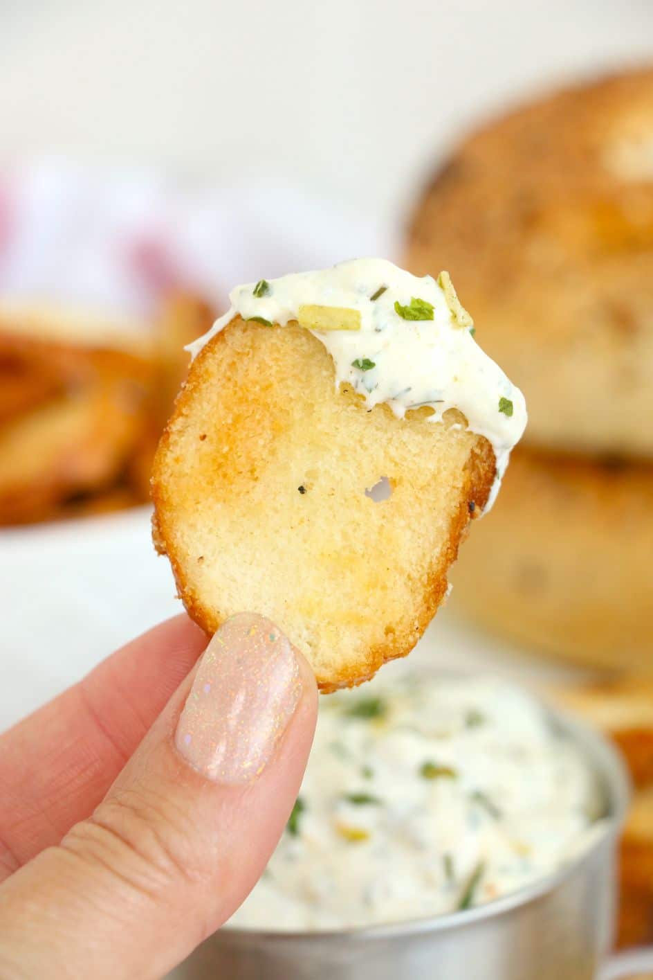 Bagel bites dipped into a creamy dip and held up with a hand
