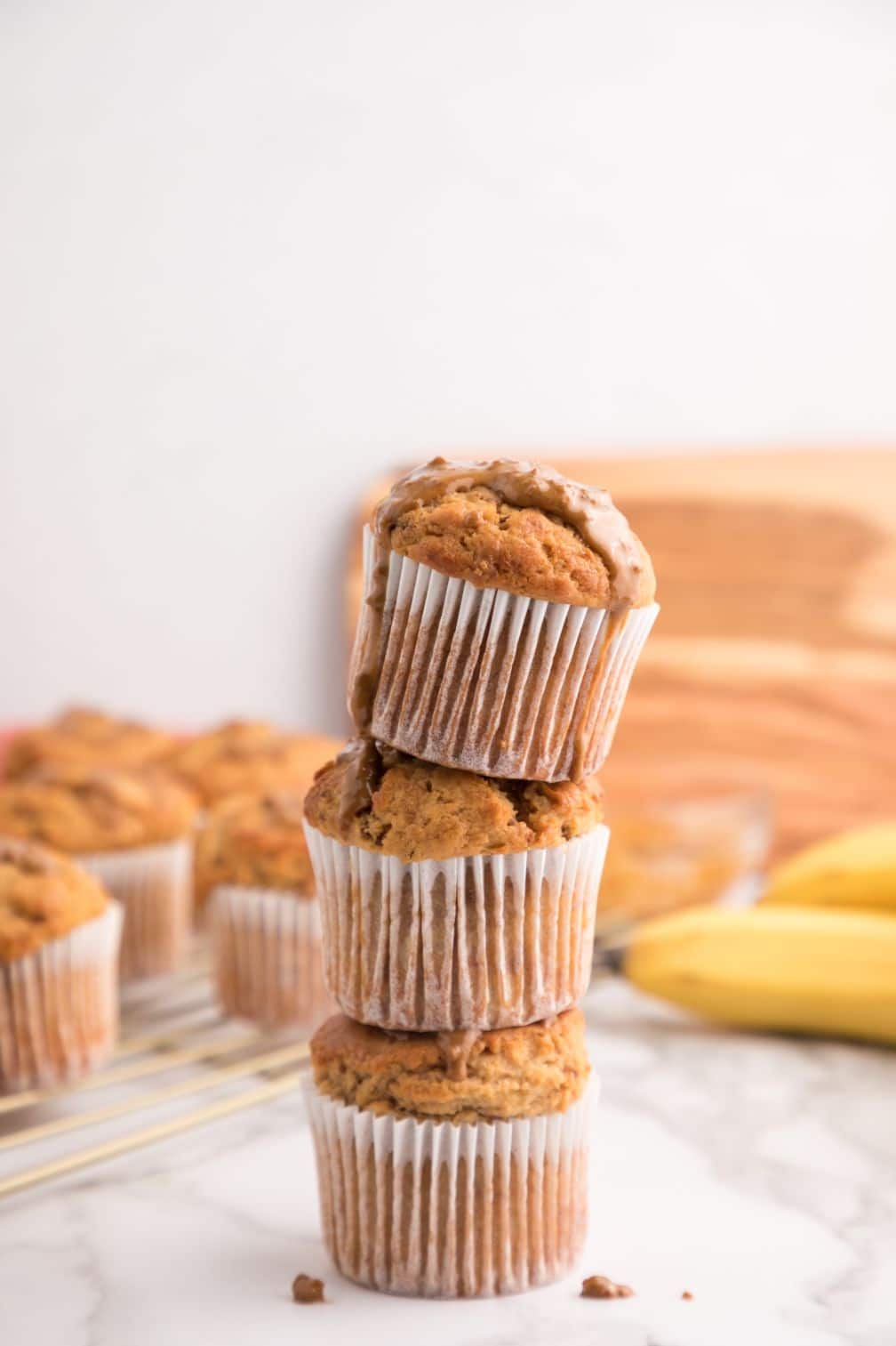 A stack of muffins with some bananas in the background