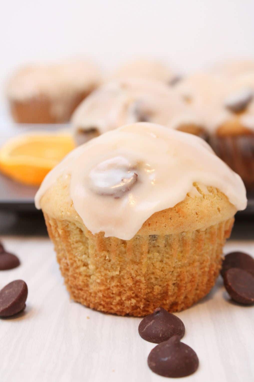 Up close shot of a dark chocolate chip and orange muffin with a glaze on top