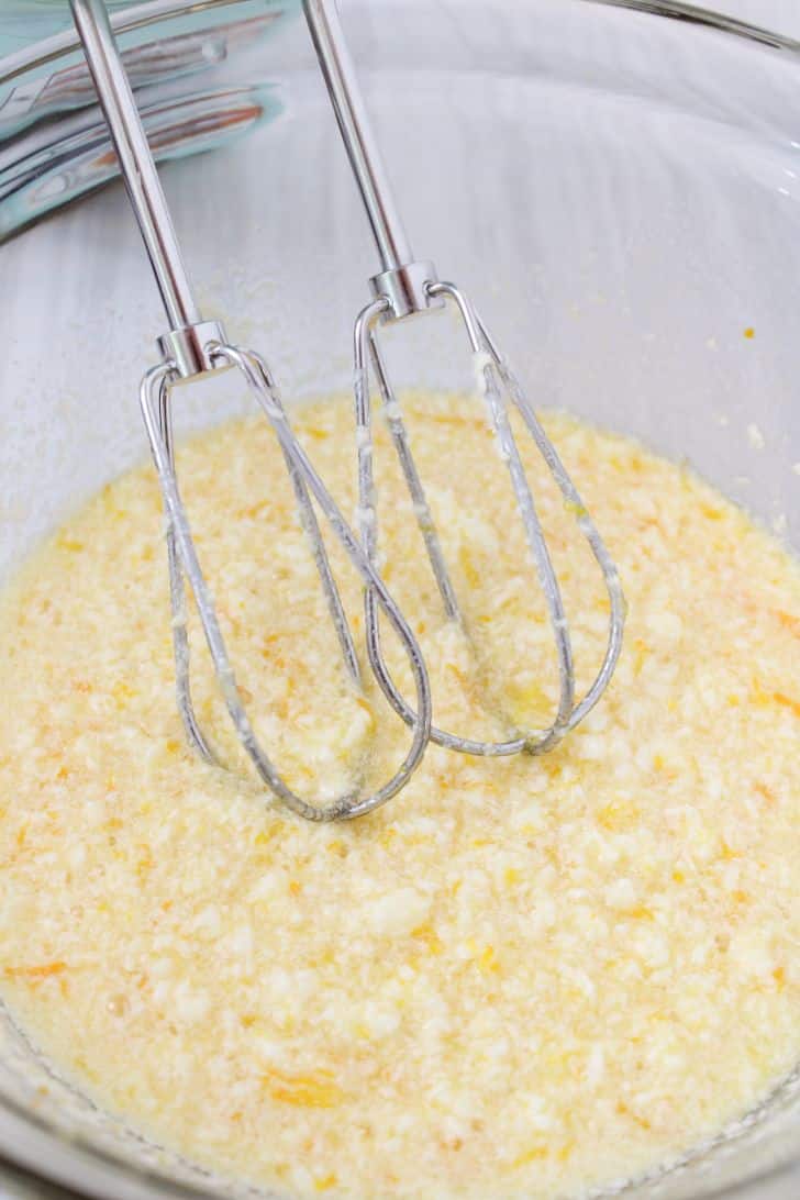 Two electric whisk heads beating butter with eggs 