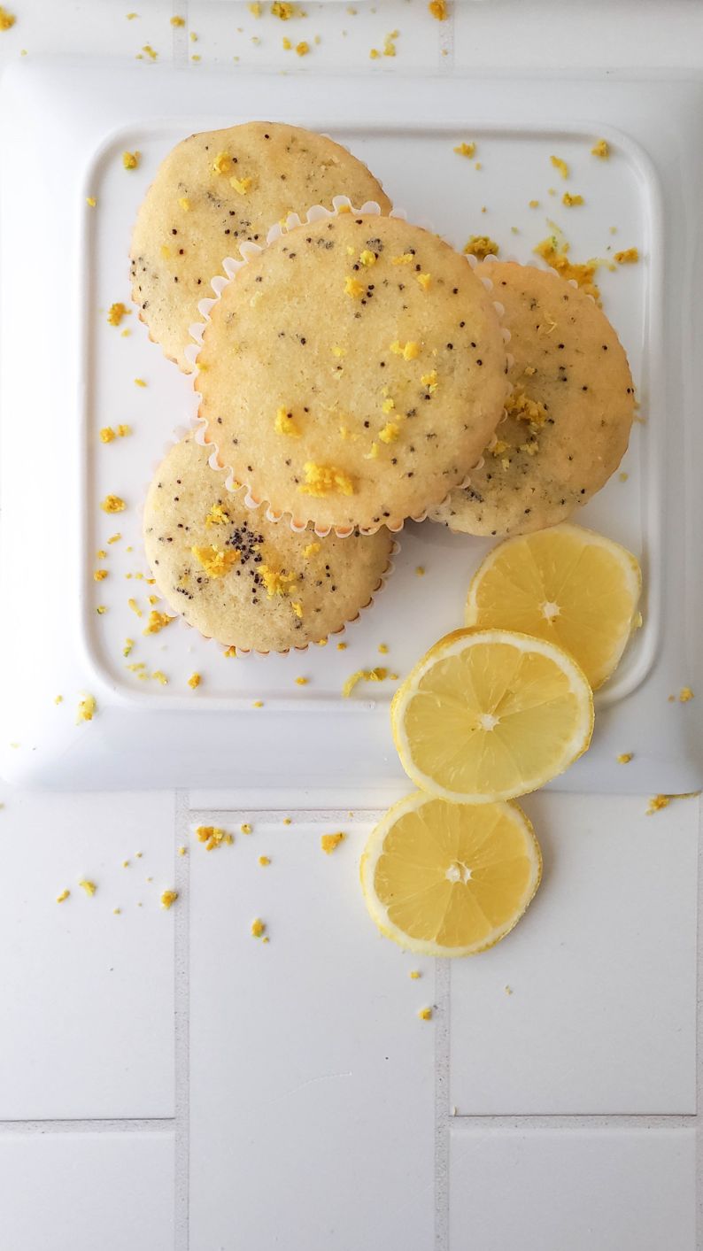 An overhead shot of a stack of muffins on an upturned plate with slices of lemon surrounding