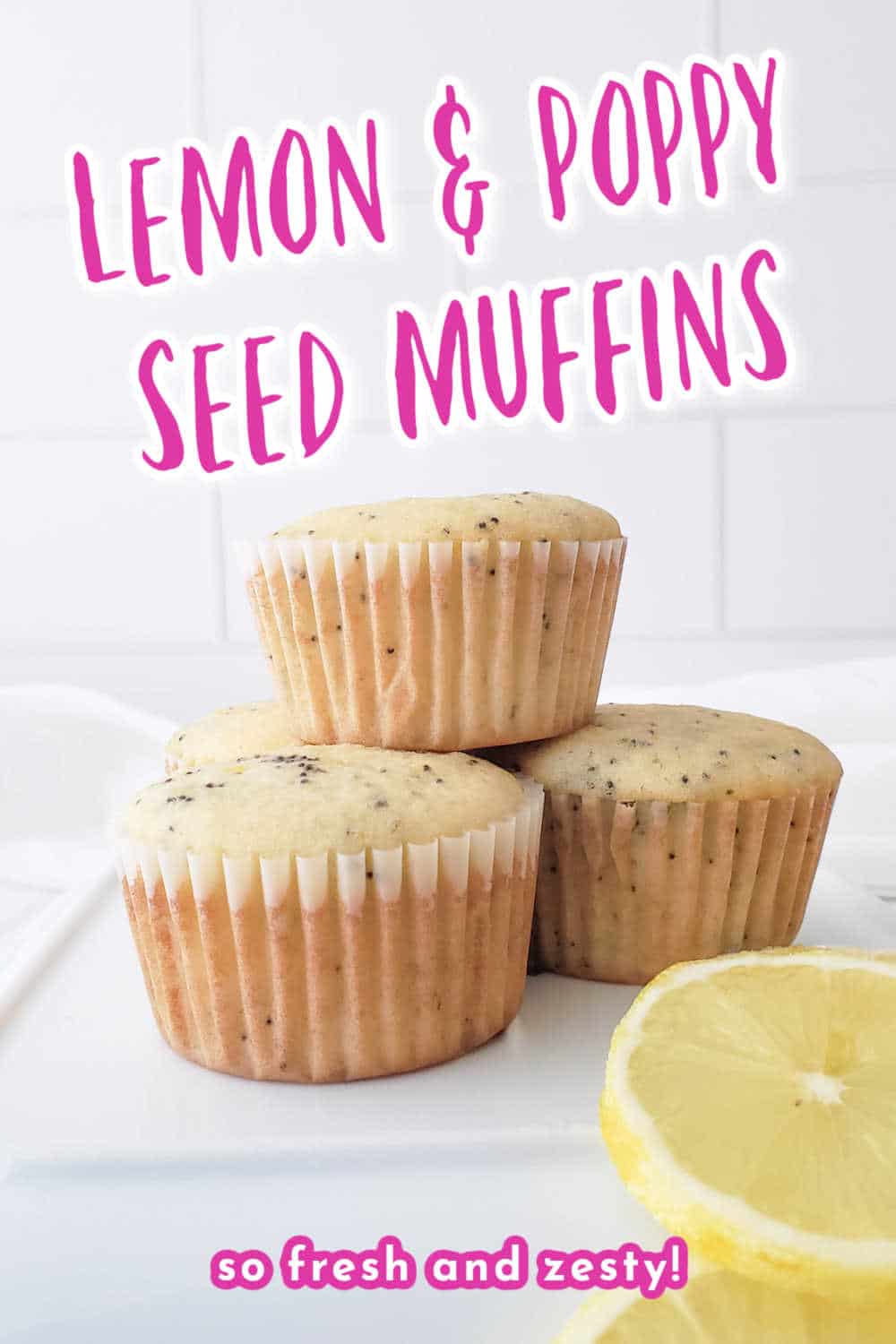 Three muffins stacked on a white plate with slices of lemon beside them