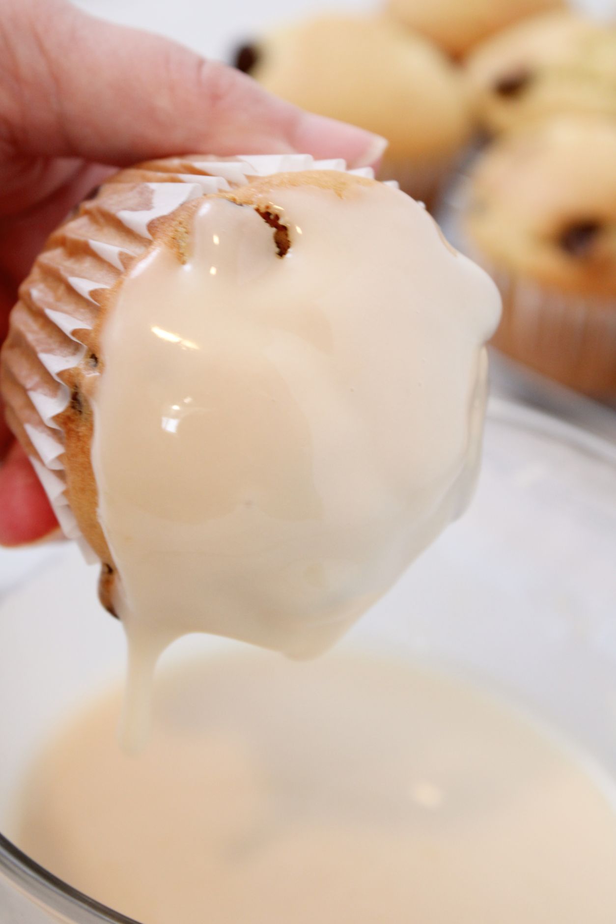 Muffins being dipped in an light orange glaze