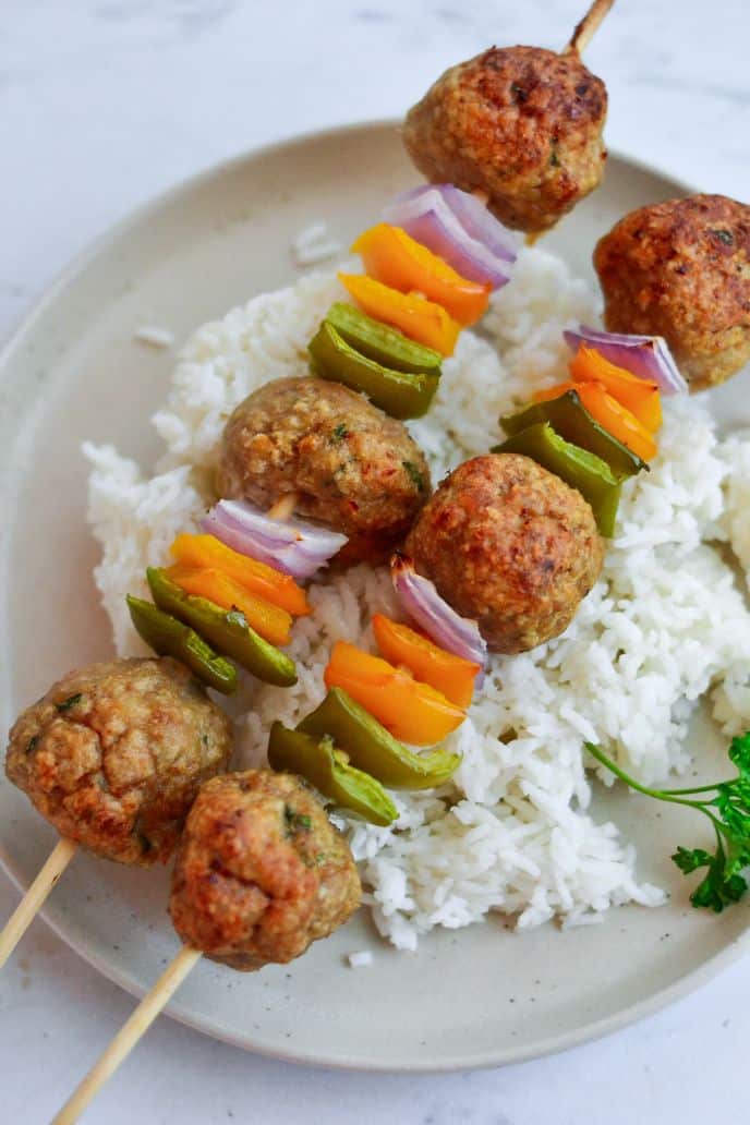 Sweet and sour chicken meatballs served on skewers with steamed rice