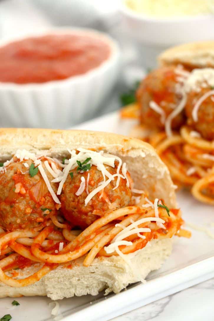 2 meatballs with some cooked spaghetti and sauce in a hot dog bun