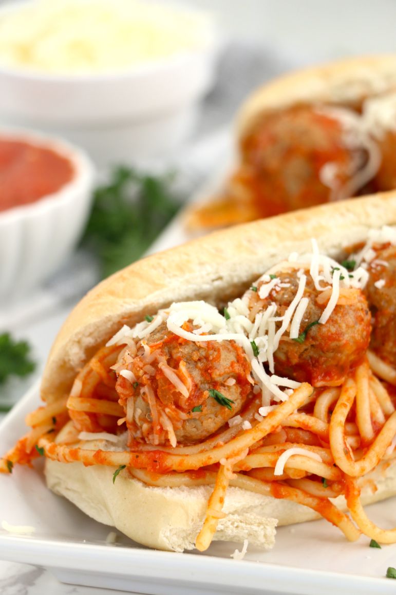 Up close shot of meatballs and spaghetti subs topped with grated mozzarella