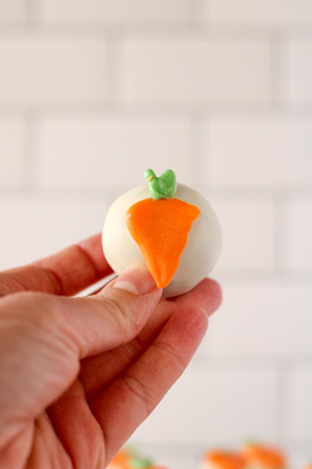 A small carrot cake ball with a candy carrot attached