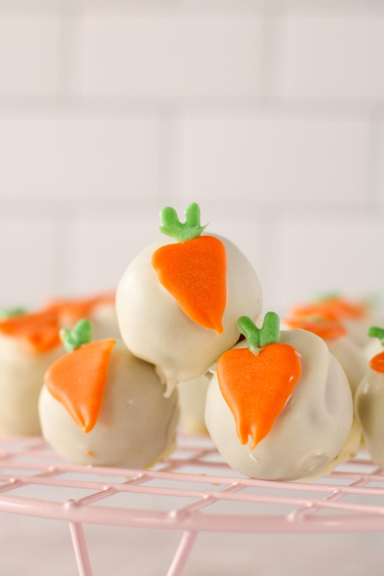 Front on image of a pile of 4 carrot cake pop balls with little carrot decorations