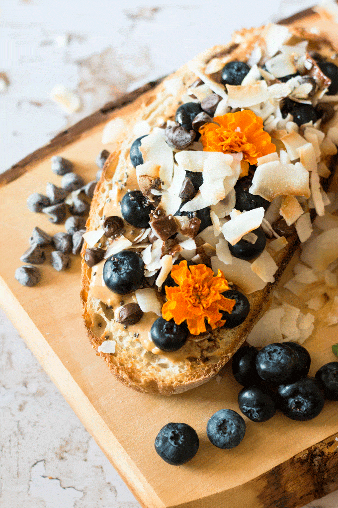 Peanut butter on toast with blueberries, banana and some edible flowers