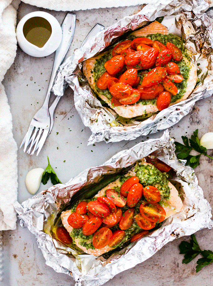 Foil parcels containing salmon, tomatoes and a salsa verde