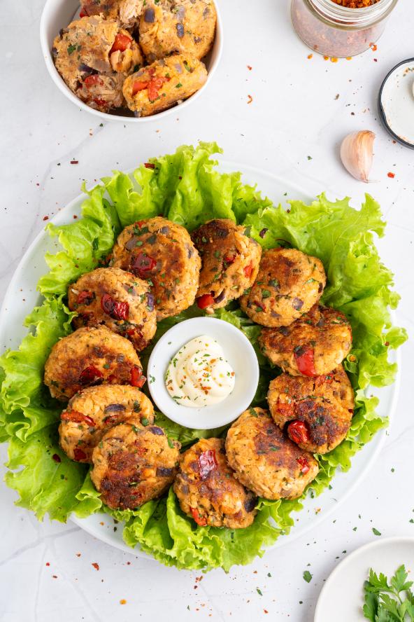 Crispy salmon bites arranged on a white plate with lettuce and a small bowl of mayo