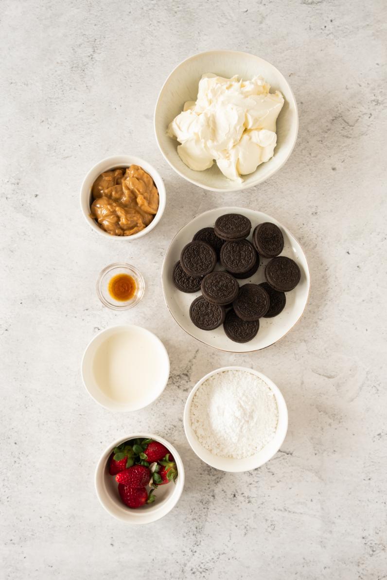 Small white bowls loaded up with ingredients require to make an oreo dessert